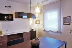 Estor paqueto a medida confeccionado en tejido traslúcido vaporoso de color blanco roto por Madegar Cortinas, instalado en un comedor elegante en Barcelona.