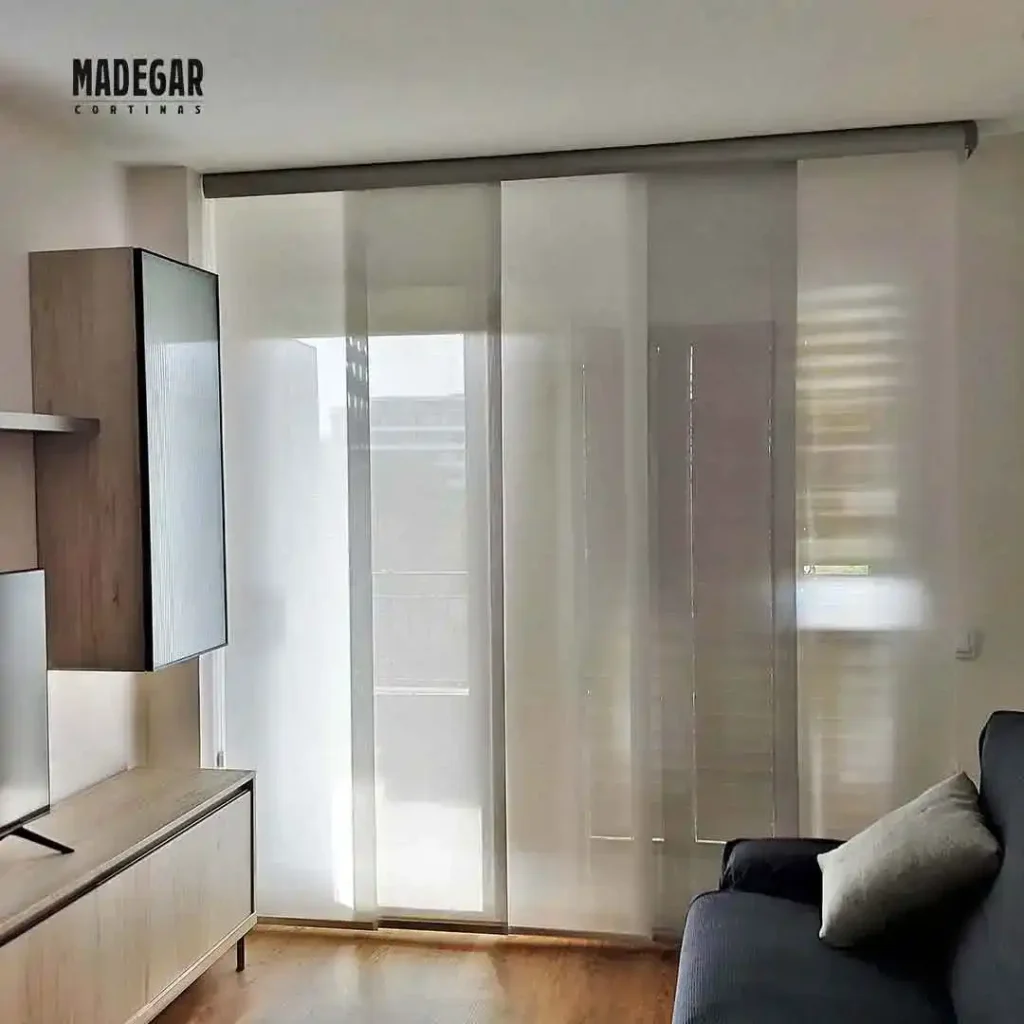 Cortinas de paneles japoneses  integradas ocupando muy poco espacio visual en un salón contemporáneo frente a un sofá oscuro y muebles de diseño en la calle Balmes de Barcelona