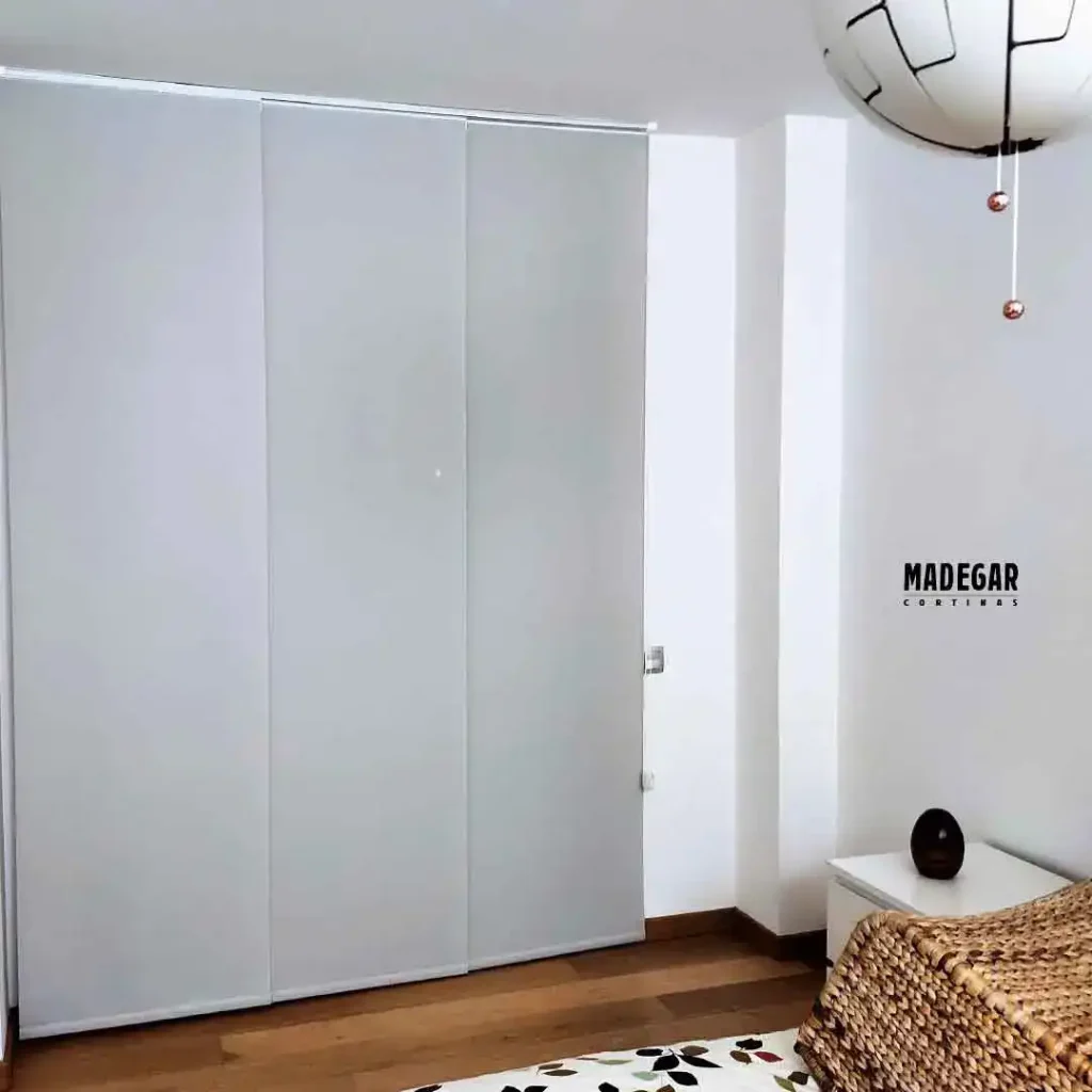 Sistema de paneles japoneses blackout en tejido técnico gris inatalado por Madegar para control térmico y oscurecimiento en un dormitorio de La Bonanova qe no tiene persianas 