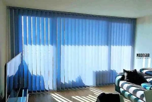 Instalación de cortinas de lamas verticales técnicas de screen azul para el control térmico en un piso muy soleado de Barcelona de diseño moderno.