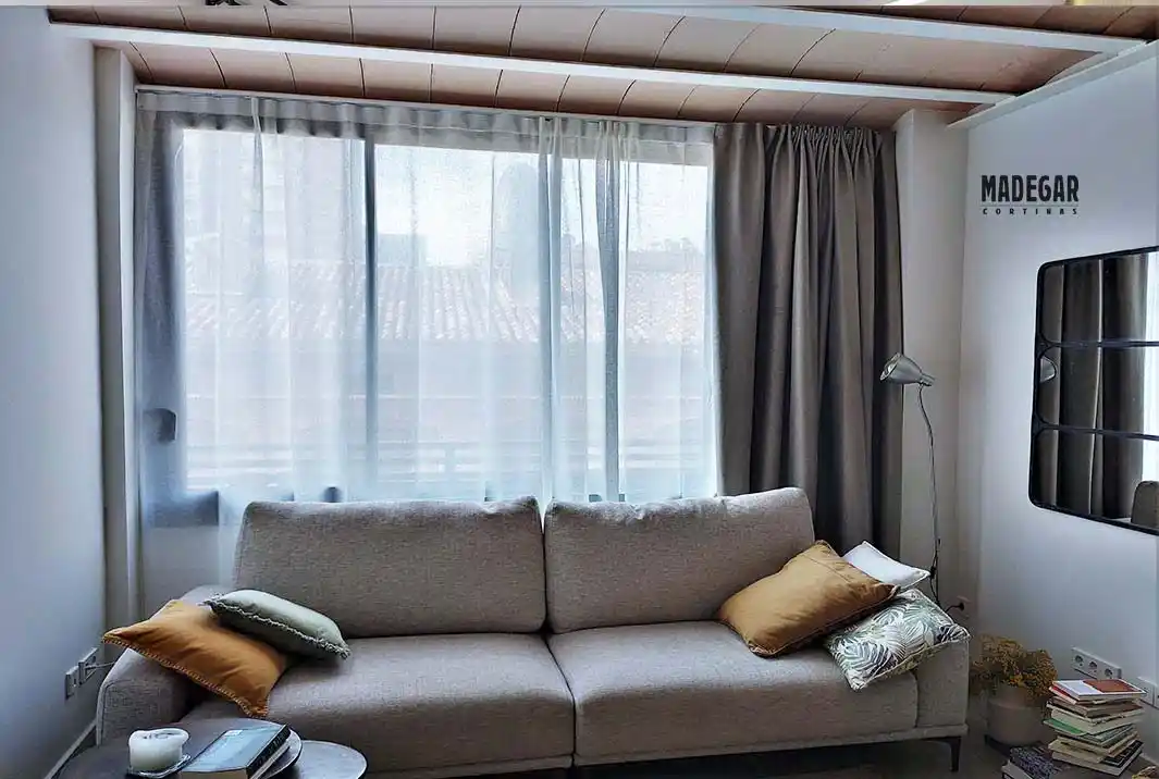 Cortinas dobles con tal transparente de lino y tejido blackout textil en un salón de estilo nórdico en colores neutros instaladas por cortinas Madegae en un riel de guia doble
