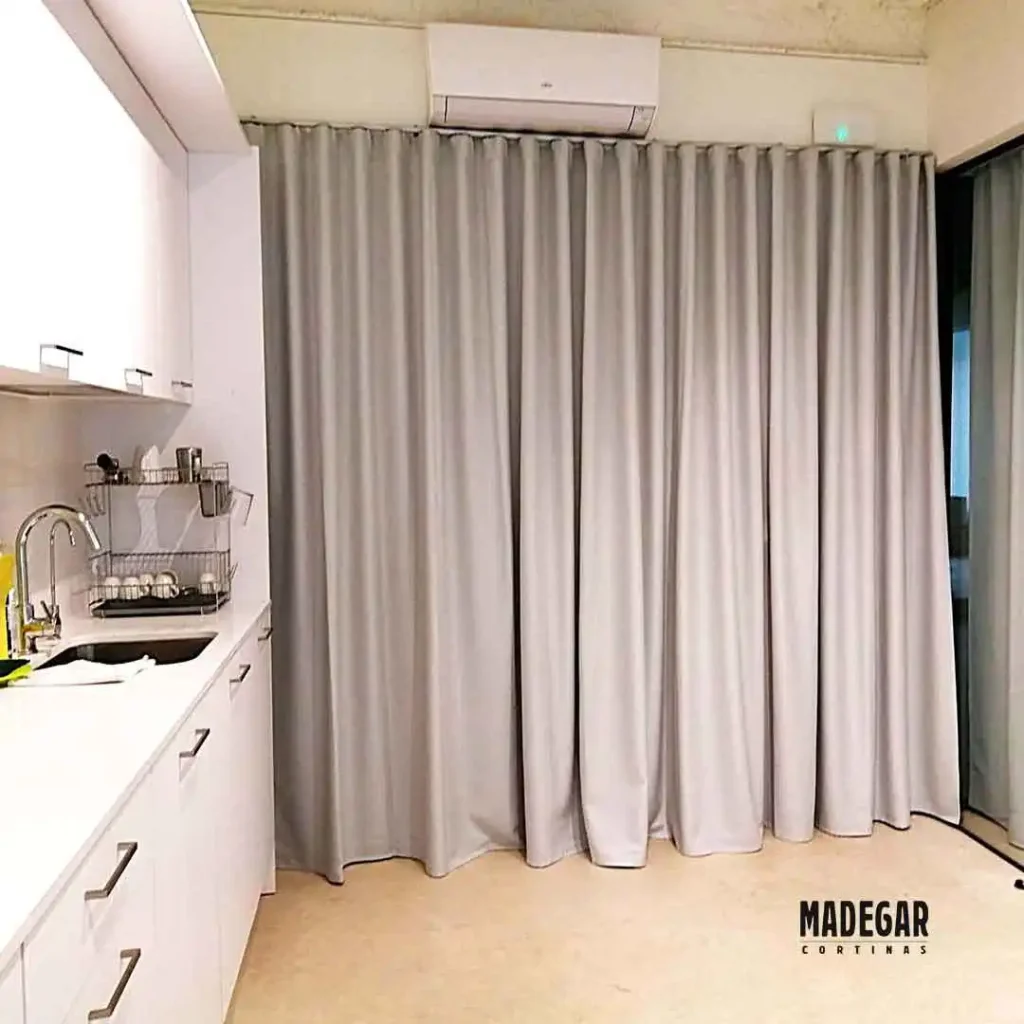 Zona de descanso y cocina en oficina del 22@ de Barcelona, separada mediante cortinas acústicas fonoabsorbentes en tejido gris instaladas por Madegar Cortinas.