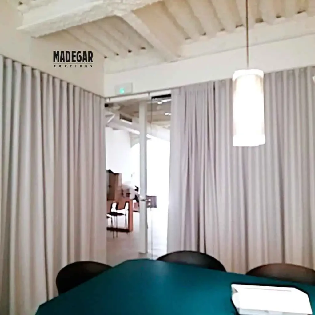 Cortinas acústicas separadoras de ambientes en posición abierta dentro de una oficina moderna en el 22@ de Barcelona. La instalación de Madegar Cortinas permite integrar o independizar espacios de trabajo de forma dinámica.
