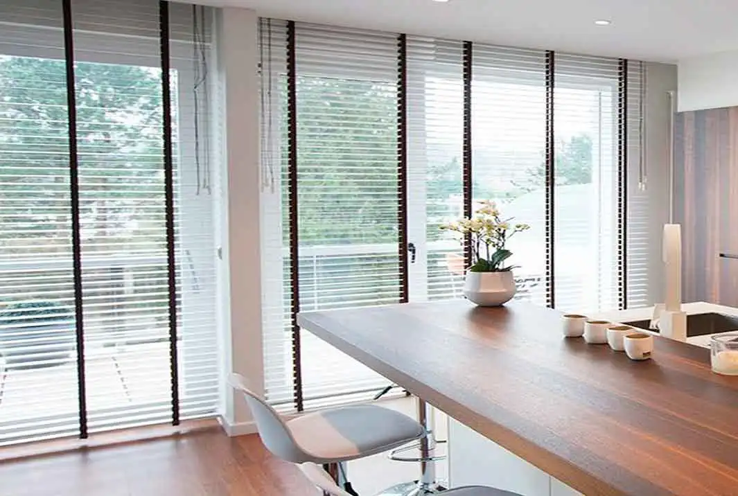 Cortinas venencias a medida en Aluminio blando personalizadas con cinta marrón oscuro en los grandes ventanales de  la cocina lujosa de estilo moderno en una casa de Alella