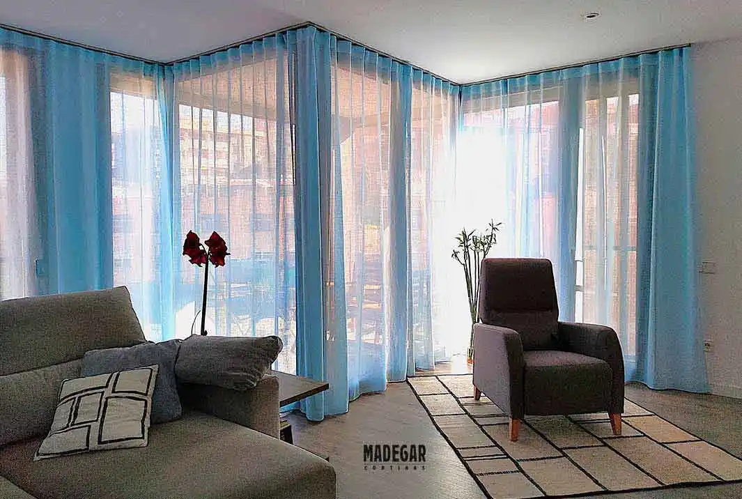 Cortinas de lino con una confección a medida exlusiva de Cortinas Madegar en color azul en una salón comedor eelegante y modernos de Barcelona