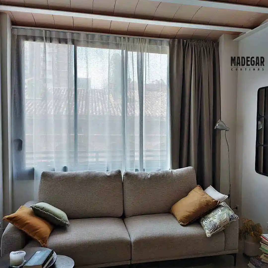 Cortinas dobles con tal transparente de lino y tejido blackout textil en un salón de estilo nórdico en colores neutros instaladas por cortinas Madegae en un riel de guia doble