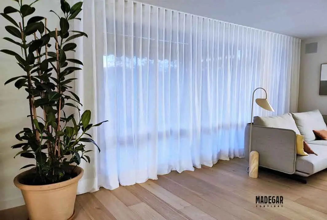 Cortinas de onda perfecta arrastrando en un salón de diseño nórdico en Barcelona instaladas y confeccionadas por Cortinas Madegar