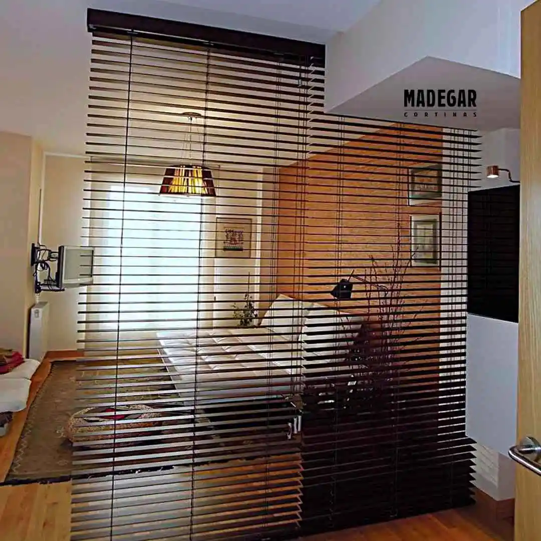 Cortinas venecianas de alumnio en negro separando el dormitorio del salón en un piso del Eixample de Barcelona