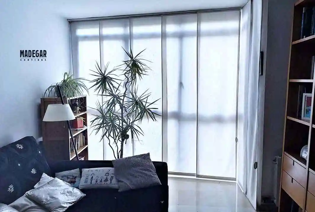 Panel japonés de loneta natural instalado en ángulo para salón pequeño en Les Corts, Barcelona, diseño a medida de Madegar Cortinas.