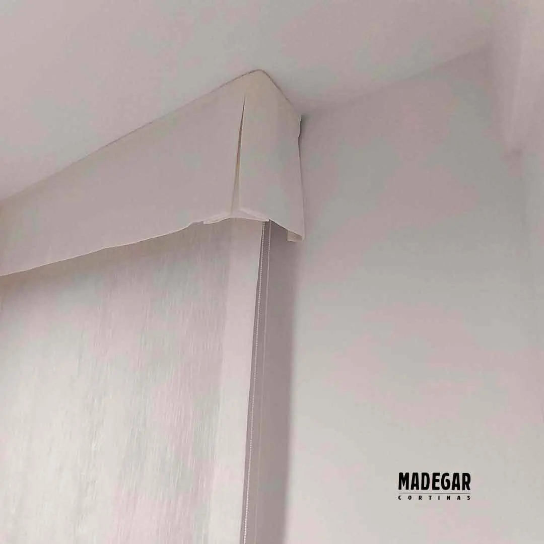 Cómo tapar el cajón de la persiana con un estor: detalle de confección de Madegar Cortinas en Vilanova i la Geltrú. Se observa el estor de semi lino instalado bajo el cajón y un volante de tela a juego que cubre la estructura de la persiana, logrando un acabado estético limpio y ganando espacio en la habitación.