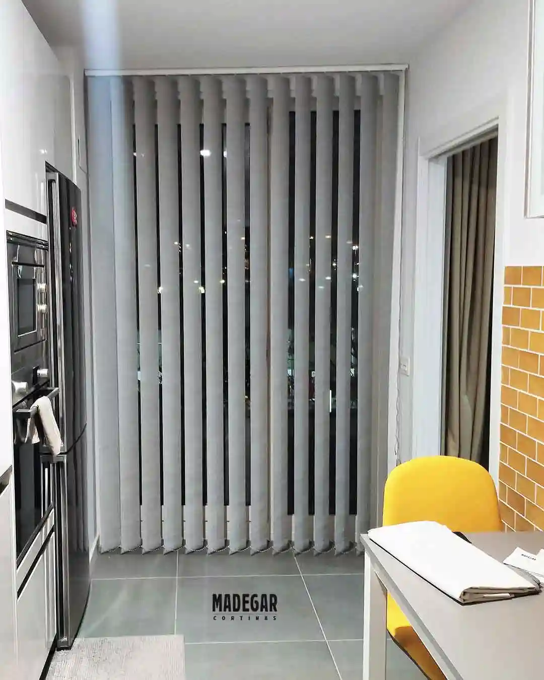 Cortina vertical de screen gris a medida instalada en una cocina moderna de Poblenou, Barcelona. El tejido técnico de Madegar Cortinas garantiza resistencia y una limpieza sencilla frente al uso diario en zonas de cocción.